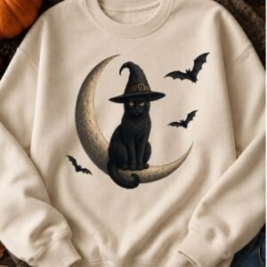 Cream crewneck sweatshirt with a black cat in a witch hat sitting on a crescent moon with bats